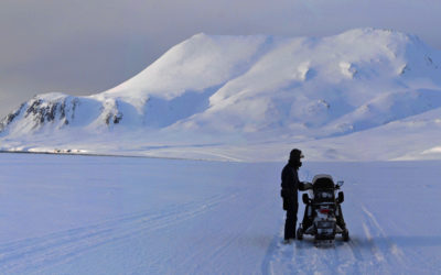 A man riding on top of a snow covered mountain.