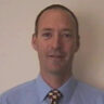 A man wearing a suit and tie smiling at the camera.