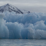 A wall of jagged ice in front of a mountain
